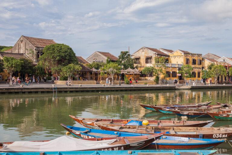 Yellow shophouses and wooden boats along the Thu Bon River in Hoi An Ancient Town