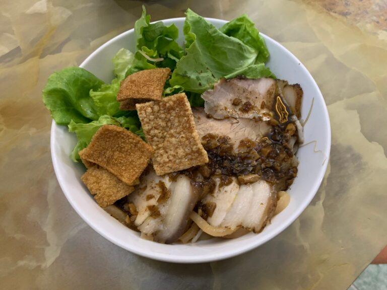 A bowl of cao lau noodles with pork, greens, and crispy croutons, Hoi An