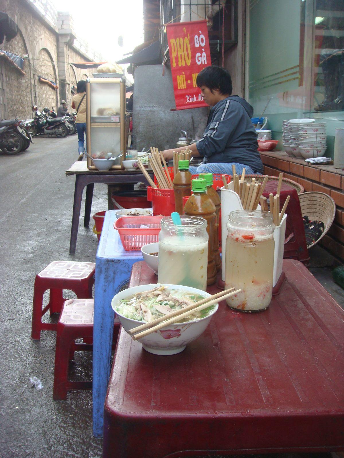 A street food vendor preparing pho noodle soup in Hanoi, Vietnam