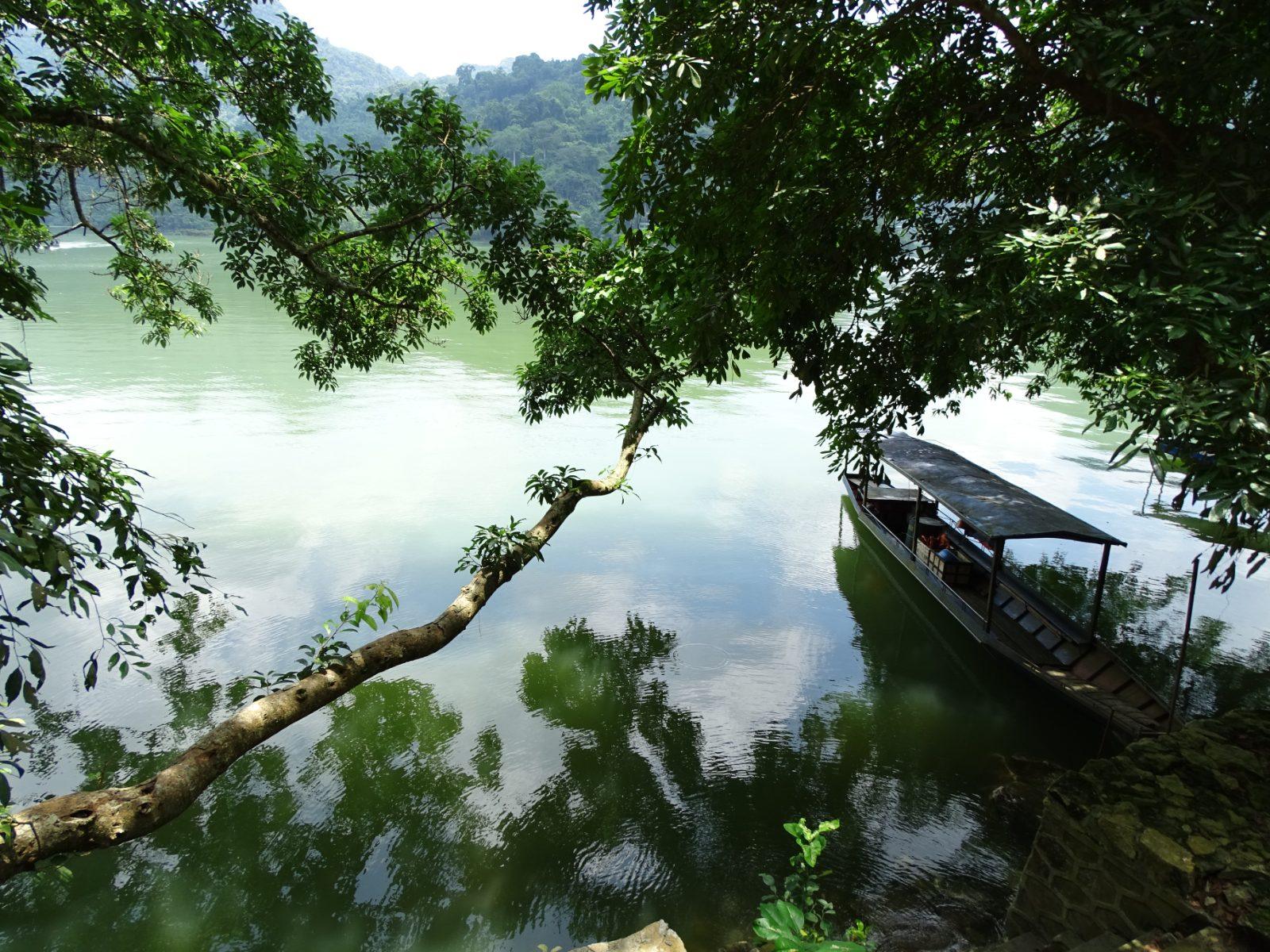 Calm waters of Ba Be Lake reflecting the surrounding limestone mountains