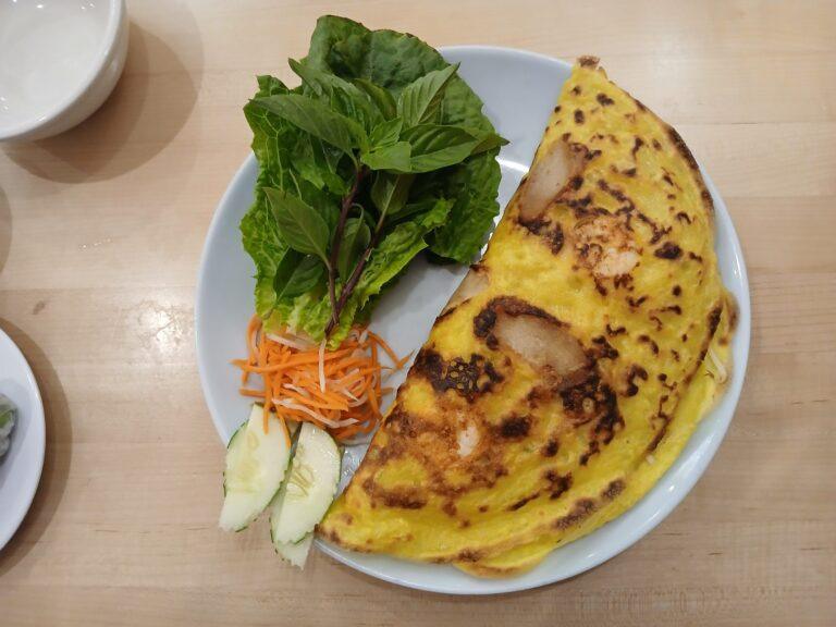 Banh xeo savory rice pancake with pork, shrimp, and fresh herb garnishes