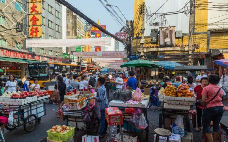 A busy street in Yaowarat, Bangkok's Chinatown, lined with food stalls and signage