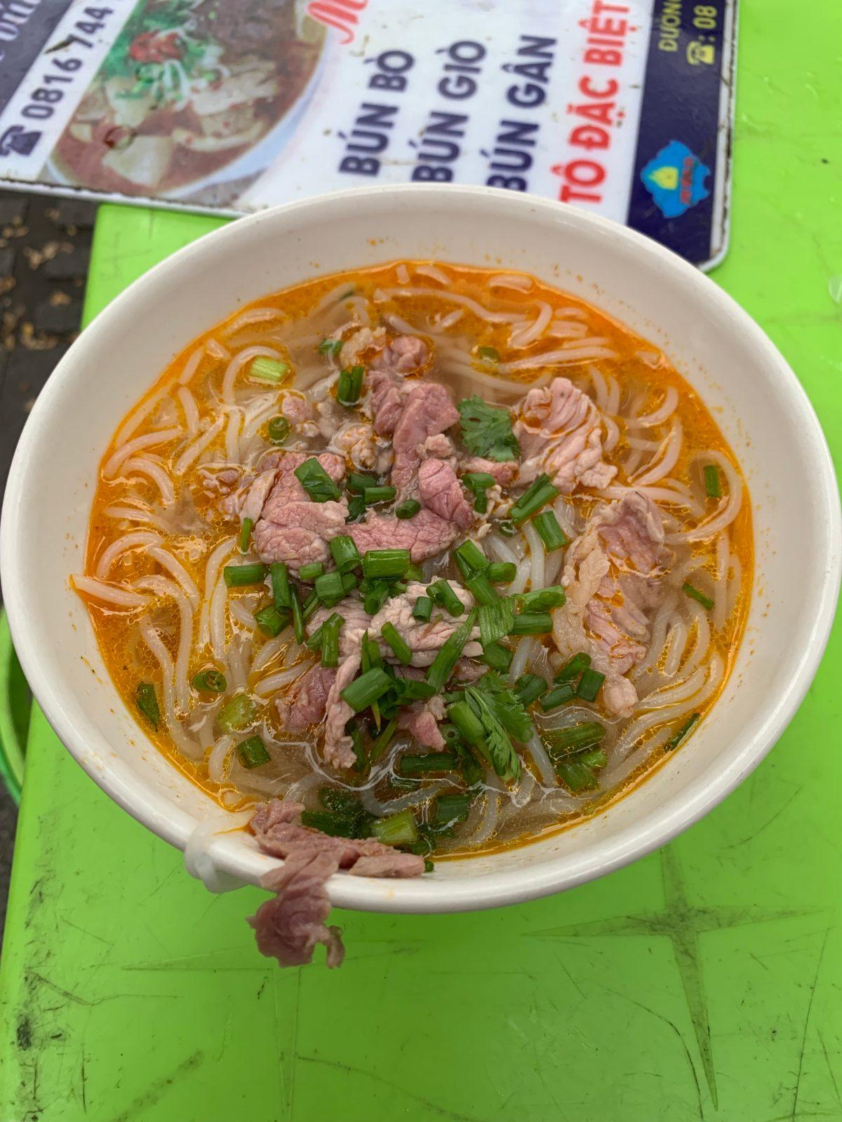 Bowl of bun bo Hue noodle soup with beef and herbs, a Central Vietnam specialty