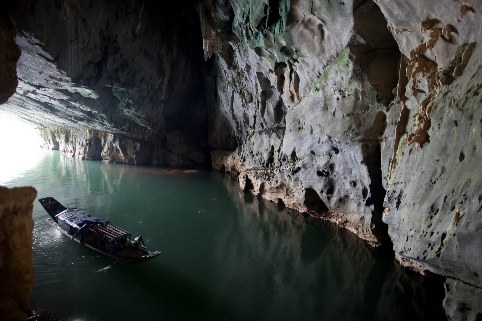 Small boat entering the river mouth of Phong Nha Cave