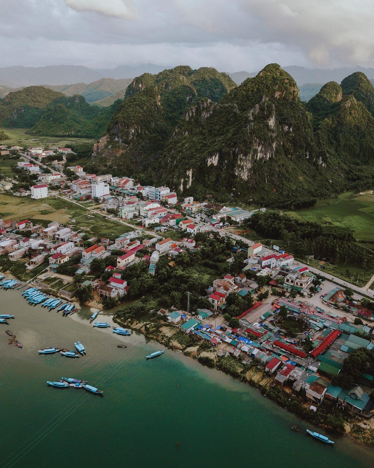 Aerial view of Phong Nha village beside the river with karst mountains behind it
