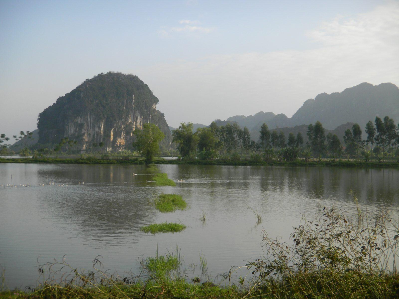 Boats rowing through karst limestone scenery at Tam Coc, Ninh Binh, Vietnam