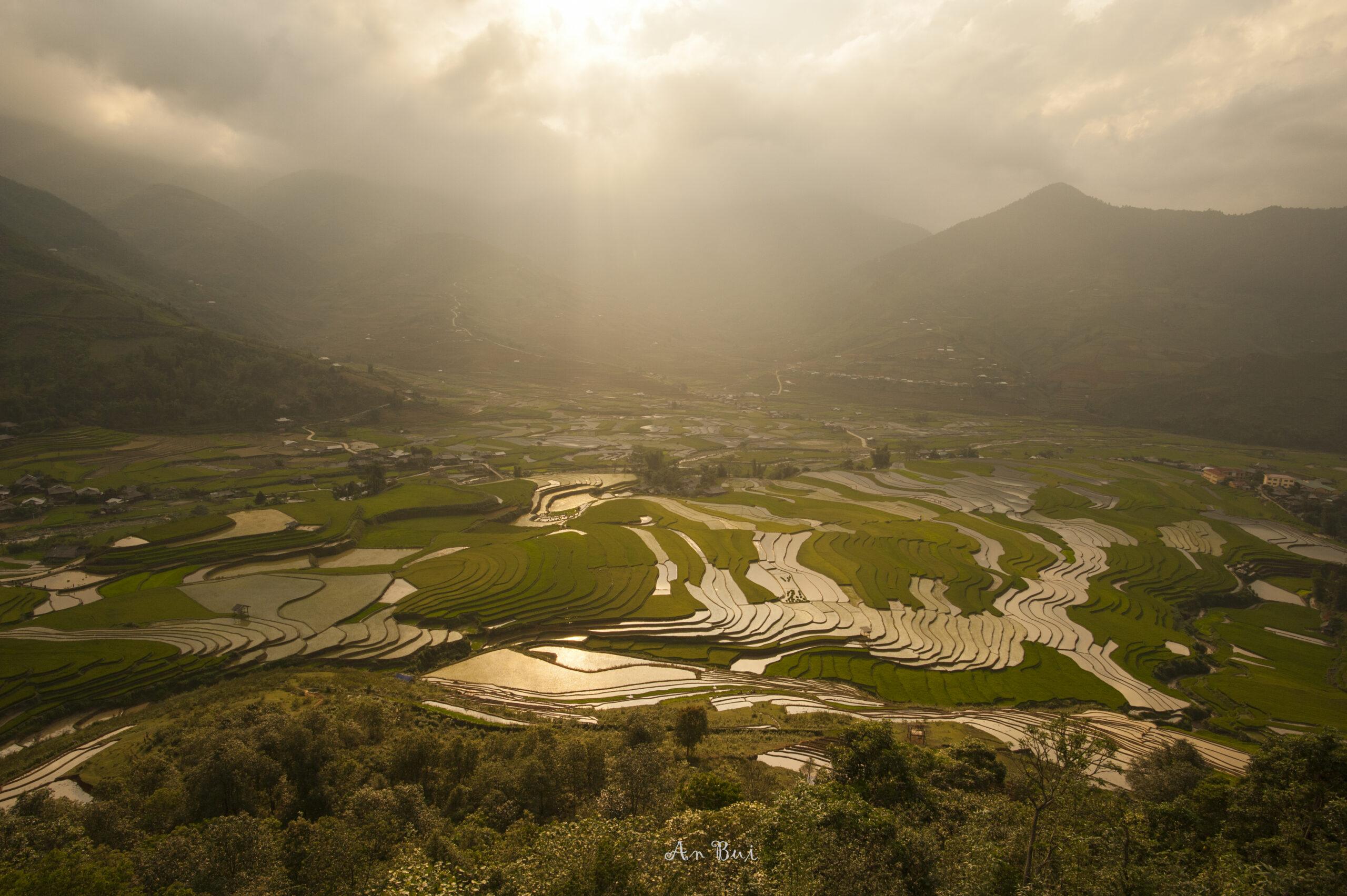 Sunbeams breaking through clouds over the water-filled terraced rice fields of Tu Le valley near Mu Cang Chai